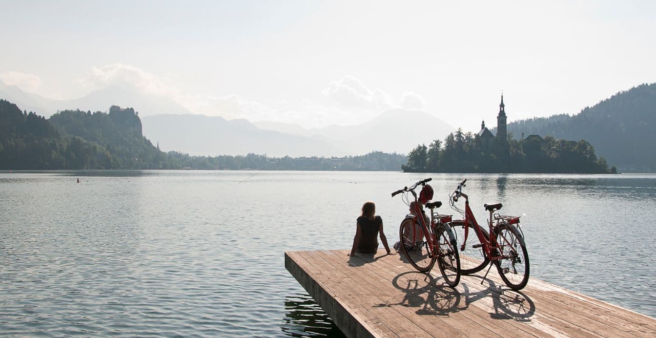 Cyclist relaxing on wooden dock beside bicycles with Lake Bled view
