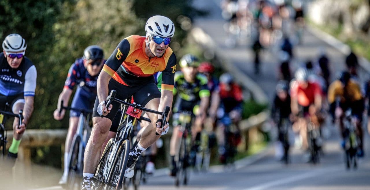 Cyclists in bright jerseys on a mountain road with a support vehicle.
