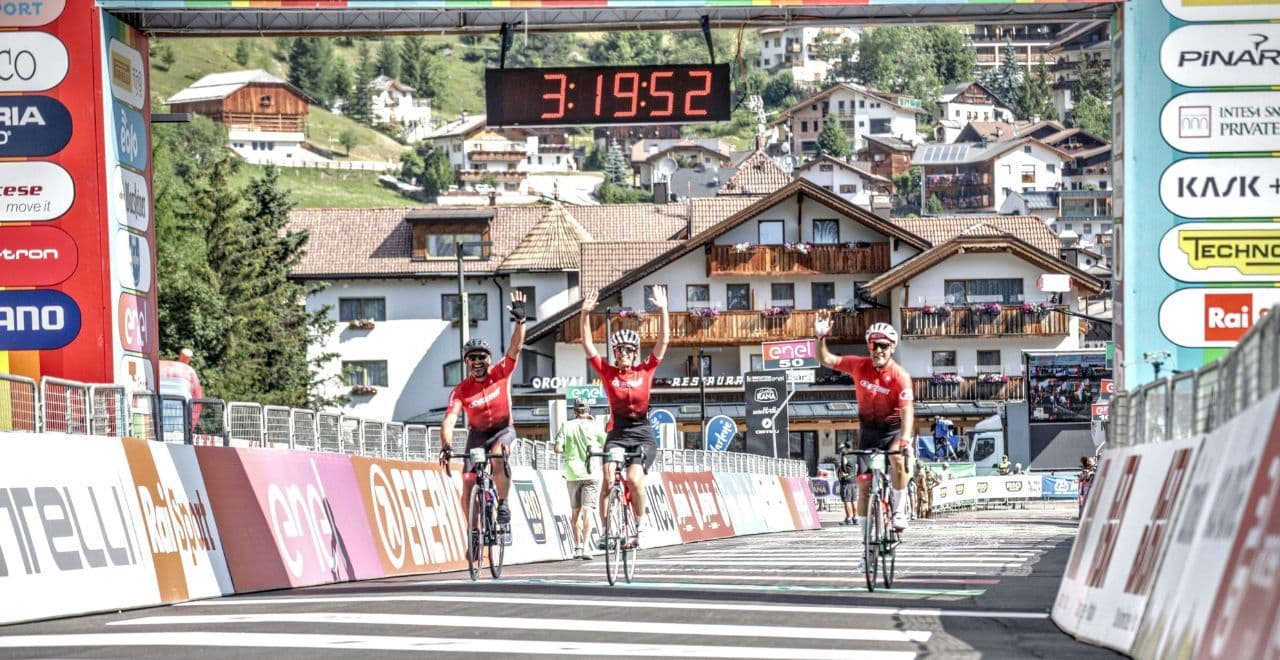 Cyclists celebrating at the finish line of a race in a mountain village.