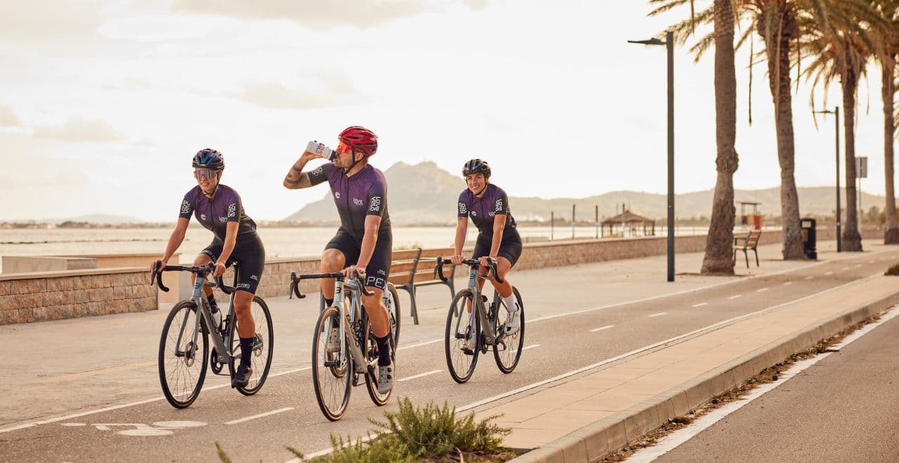 Three cyclists riding along a coastal bike path in Pollensa, Mallorca