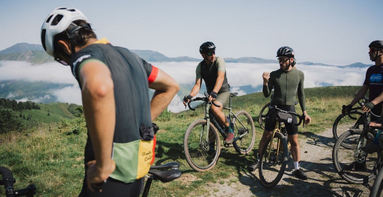 Cyclists resting and chatting on mountain summit above clouds