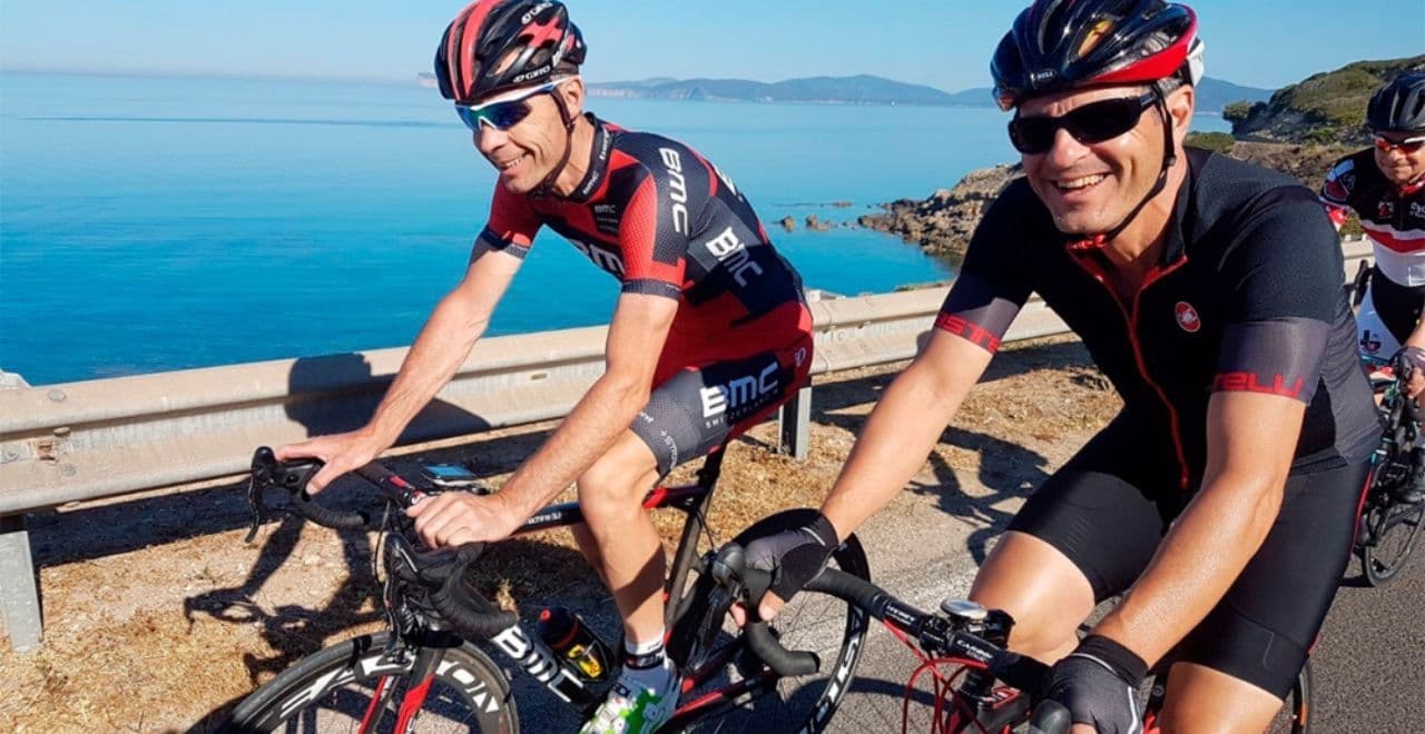 Smiling cyclists riding road bikes along scenic coastline