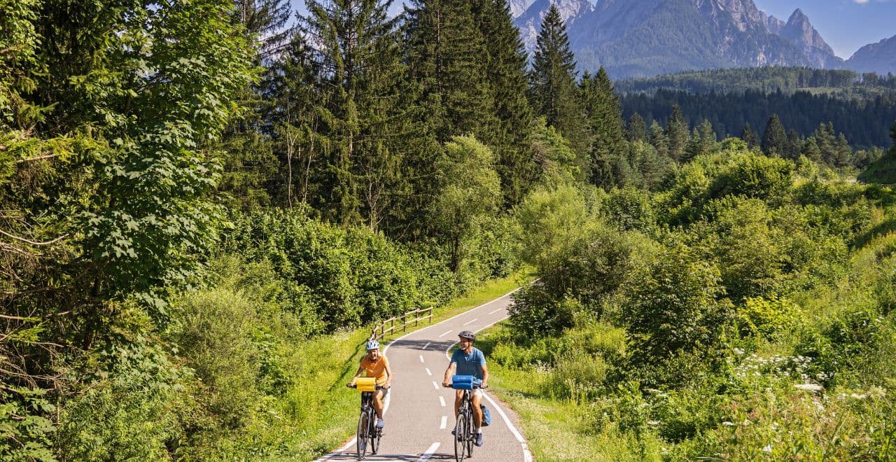 Couple cycling on a scenic forest path with mountain views