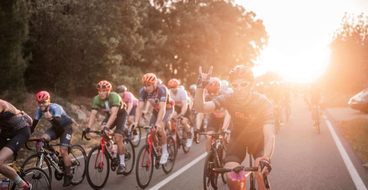 Cyclists enjoying a sunrise ride at the Mallorca 312 with one rider making a victory gesture and others following