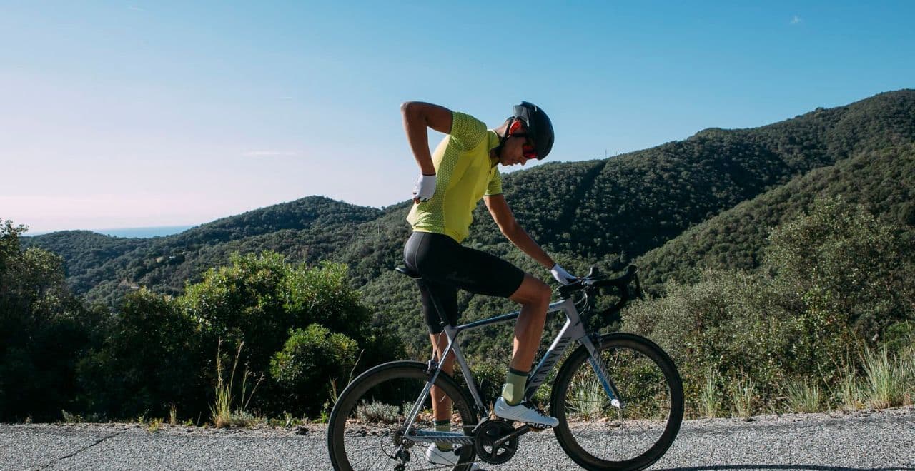Cyclist adjusting jersey on mountain road with scenic view