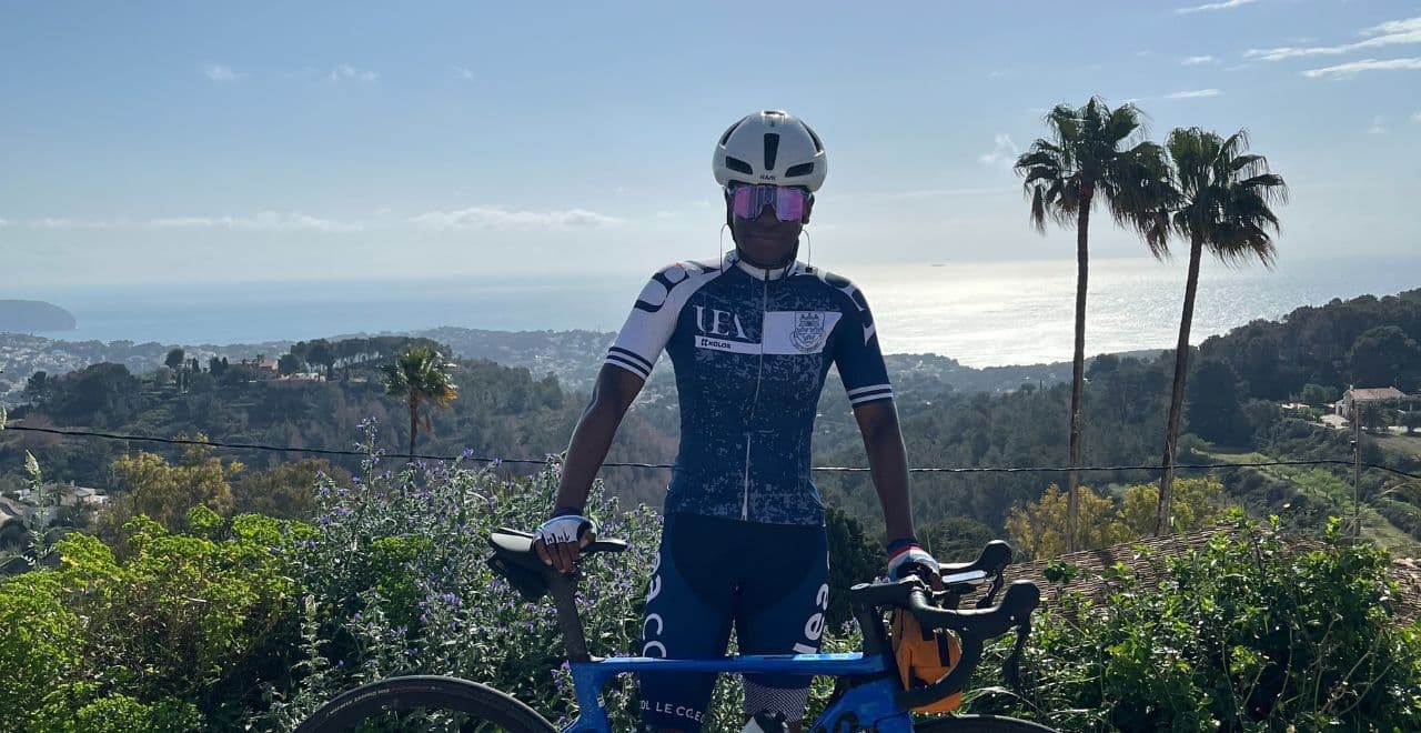 Cyclist posing with a road bike overlooking a scenic coastal view with palm trees and distant ocean