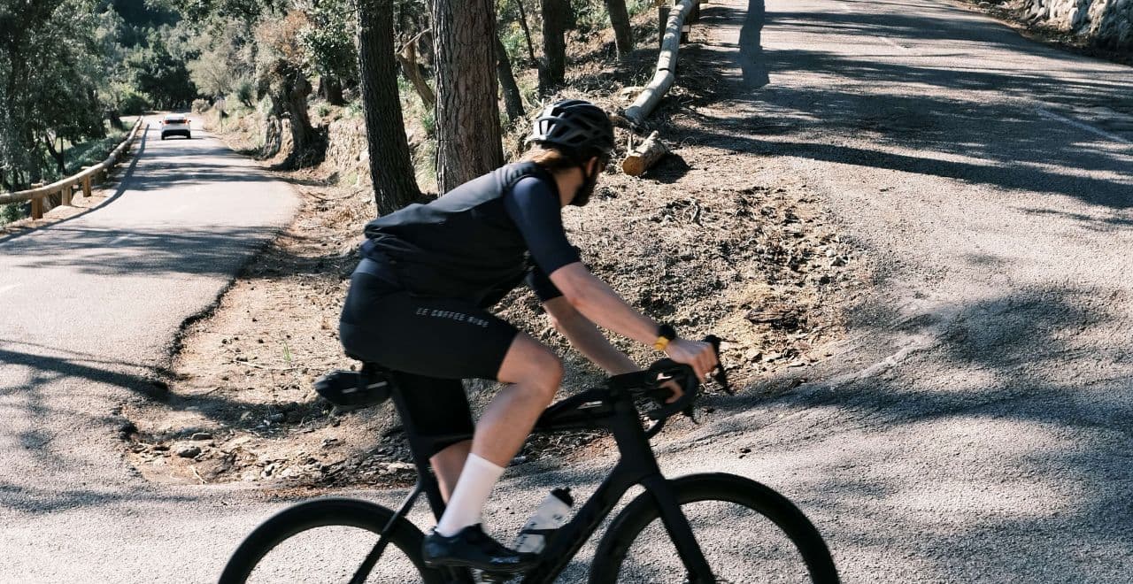 Cyclist riding uphill on forested mountain road.