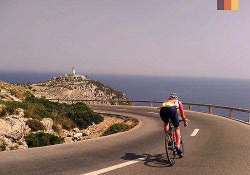 a road cyclist on the road to cap formentor lighthouse on mallorca's northern tip