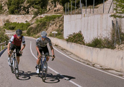 2 cyclists riding up a hill in the sunshine in Mallorca