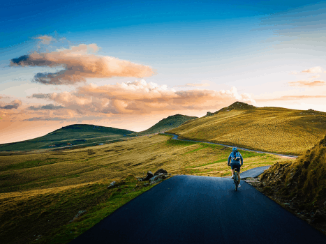a road cyclist in the yorkshire dales between hills at sunset
