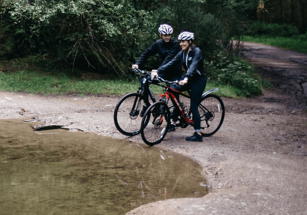 2 cyclists on mountain bikes next to a stream